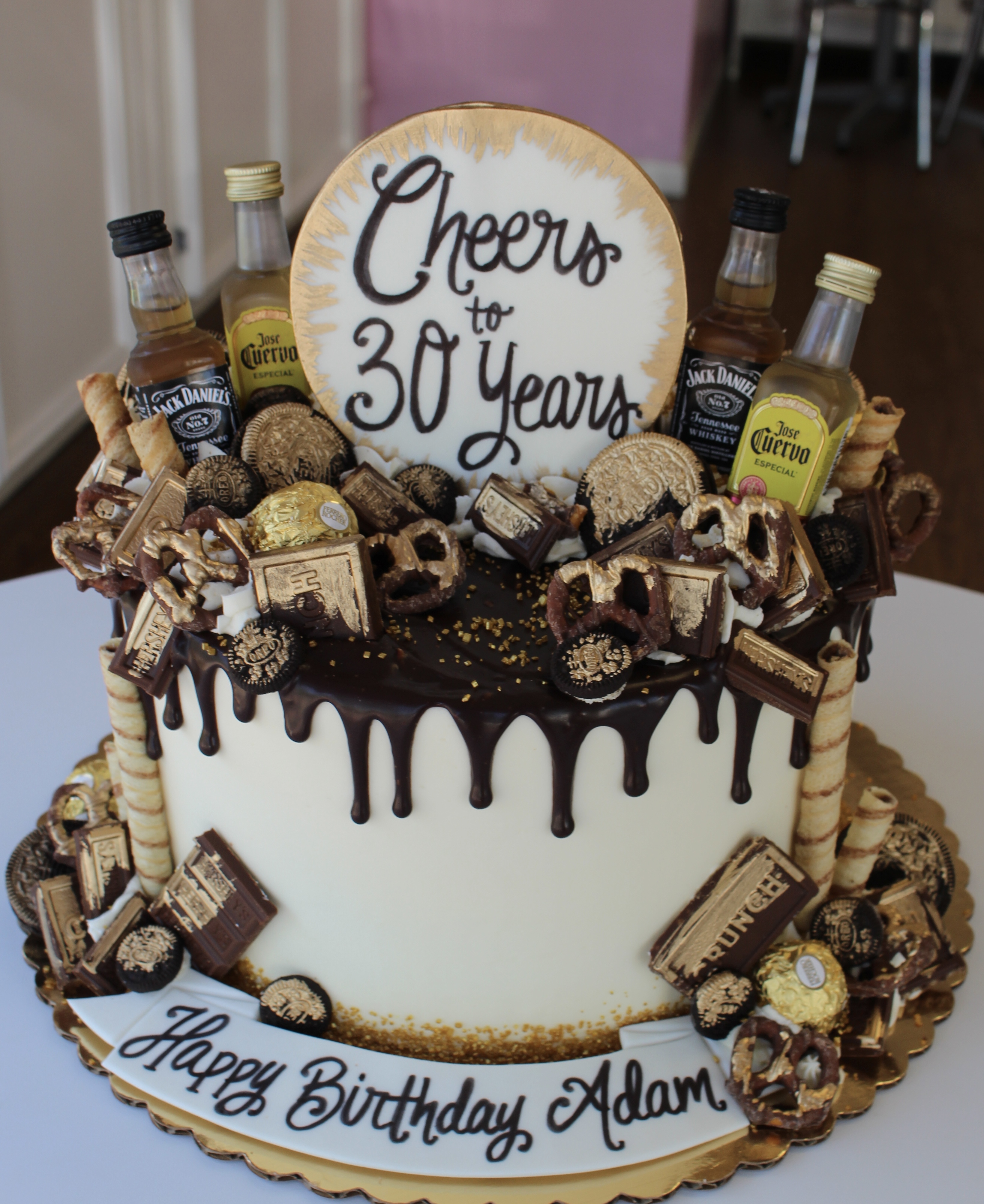 Gold and White Chocolate Drip Birthday Cake with Gold Brushed Candies and Mini Bottles