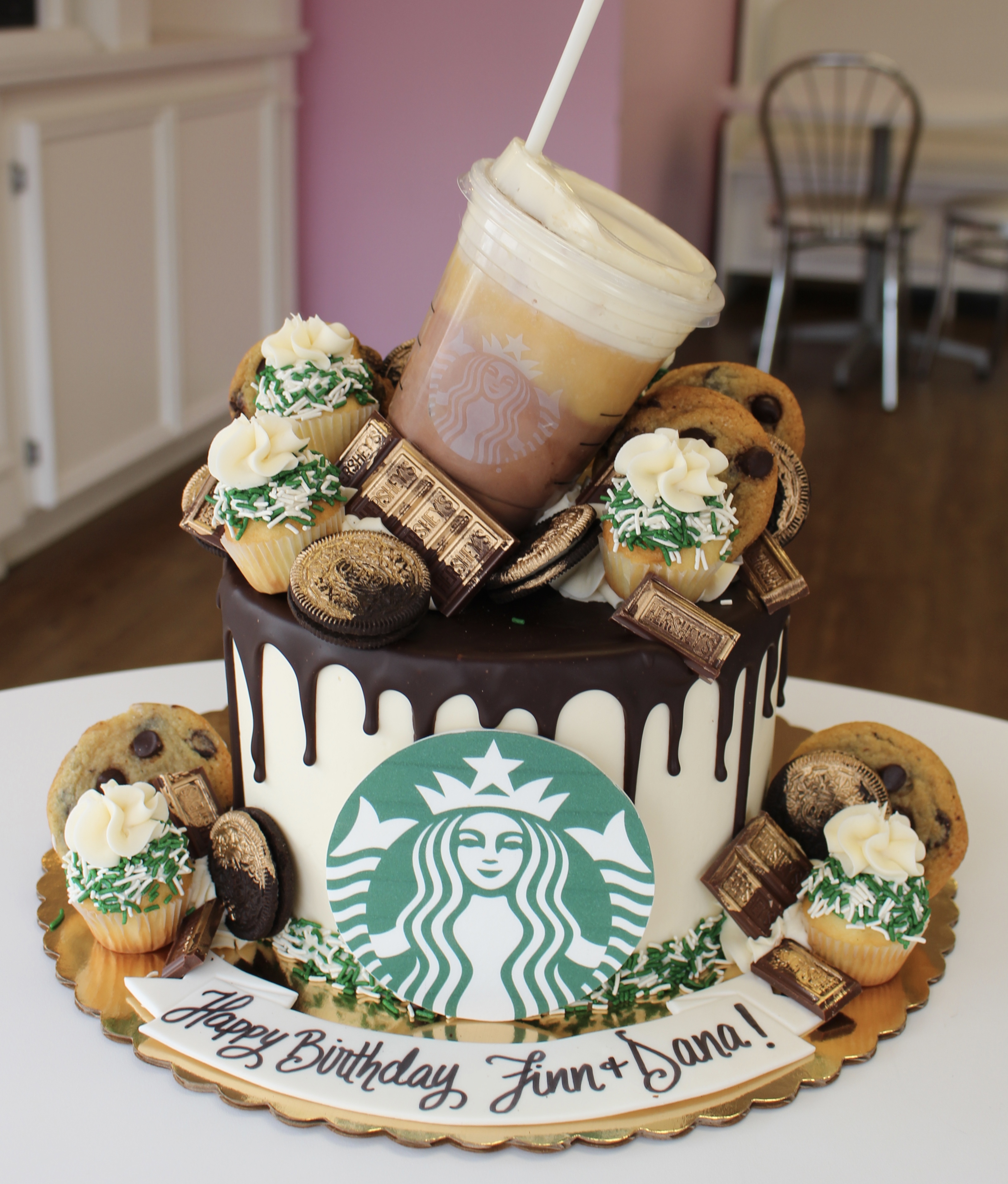 White Starbucks Drip Cake Topped with Cookies Gold Brushed Candies and a Real Starbucks Cup